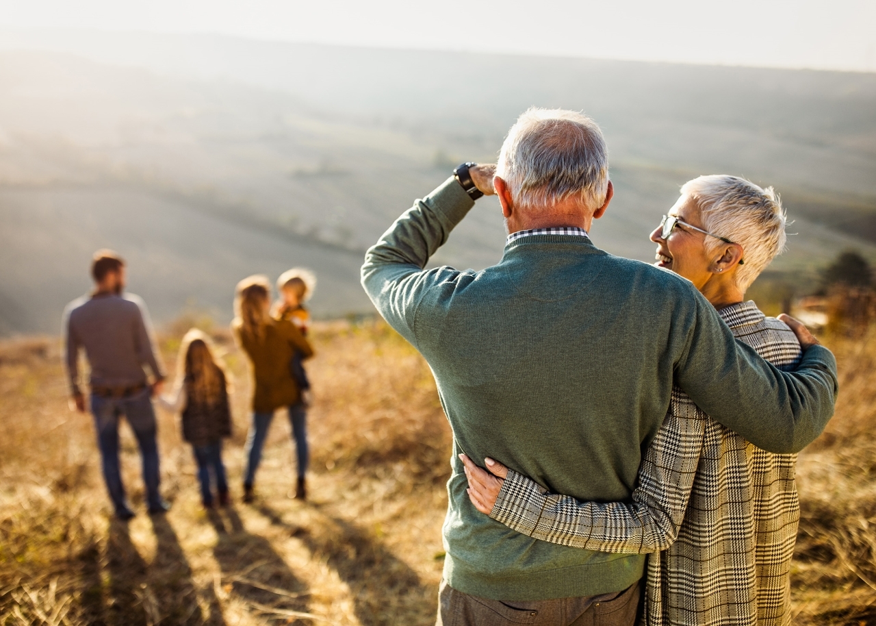Embracing Grandparents Looking at Family on Hill